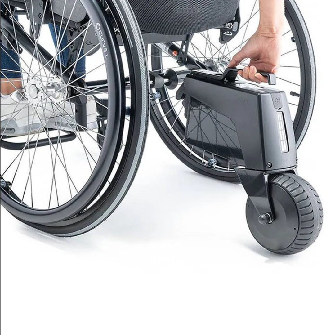 A personās hand removes a battery from the Alber SMOOV One Power Assist attached to the rear wheel of a manual wheelchair.
